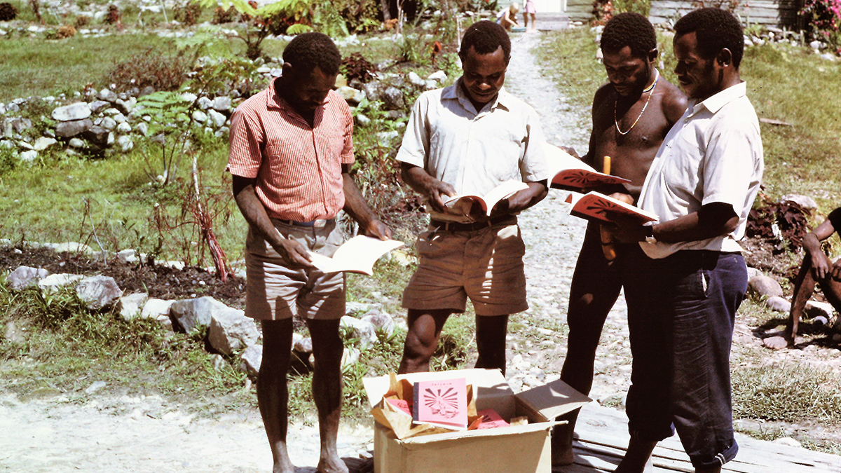 Members of the Damal Tribe perusing John’s Gospel in their own language just delivered by MAF