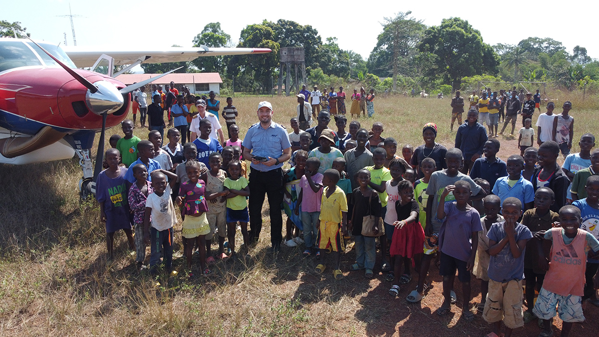 Dave Waterman & MAF plane surrounded by children in Tapeta, eastern Liberia