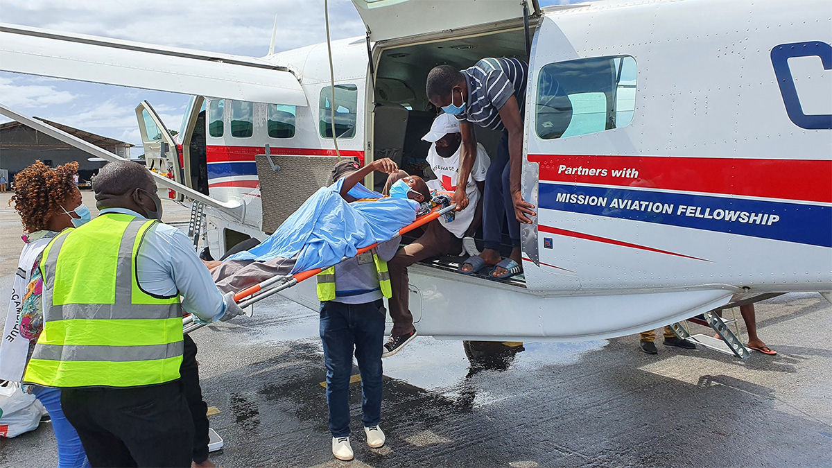 A wounded evacuee is unloaded at Pemba Airport and met by the Red Cross 