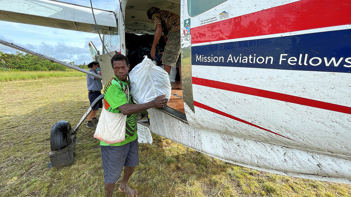 A bale of mosquito nets is unloaded at Edwaki Airstrip