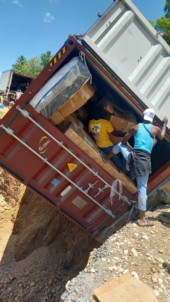 Locals unload the truck in a bid to set it upright (credit: Lemuel Ministries)